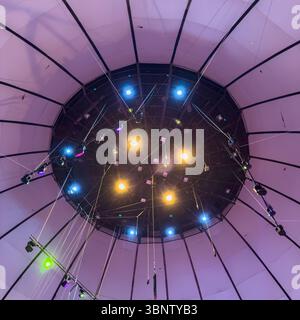 Image of the interior circus dome ceiling with stage lighting, spotlights, cables, and rigging. Abstract radial composition. No people. Stock Photo