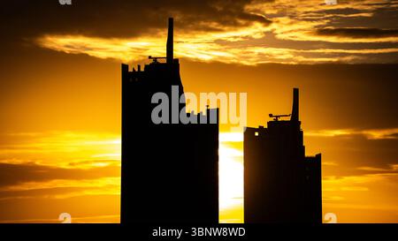 High-rise buildings silhouetted against a fiery golden sunset Stock Photo