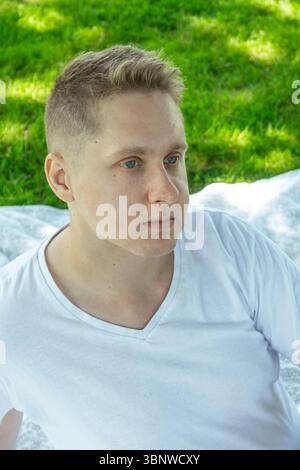 A young man, in a thoughtful pose, finds tranquility in natures calming beauty Stock Photo