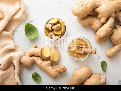 Fresh ginger root slices with melted ginger powder on light kitchen background. Stock Photo