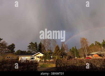 Rain clouds and rainbow over Finnish residential area, Finland Stock Photo