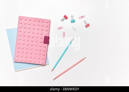 Brightly colored stationery is arranged on a smooth white surface. Two pencils, paper clips, and a notepad create an inviting workspace ready for crea Stock Photo
