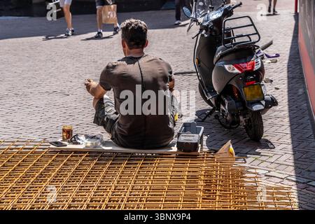Construction workers taking their lunch break, sitting on wire mesh in front of the construction site. Stock Photo