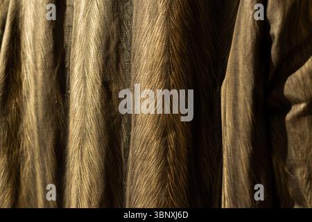 Elegant fabric texture with subtle vertical stripes in warm brown and gold tones. Ideal for fashion, textile, and abstract backgrounds. Stock Photo
