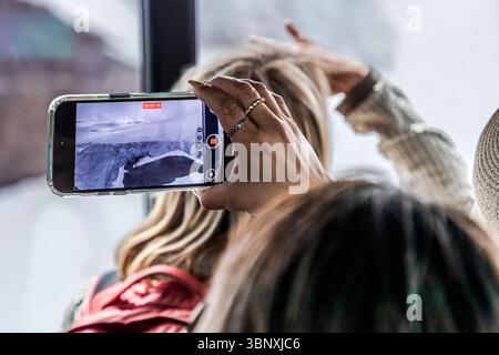 Visitors can enjoy spectacular panoramic views from the Rotair gondola lift, which rotates 360 degrees on its way up to 3,020 metres. Tourists crowd into the gondola, holding up their mobile phones, making it impossible to enjoy the view. Once at the top, visitors can expect to see a major construction site until 2029. A person captures the breathtaking glacier landscape with their smartphone. She is in the Titlis Rotair cable car to document the spectacular view. Wolfenschiessen, Nidwalden, Switzerland Stock Photo