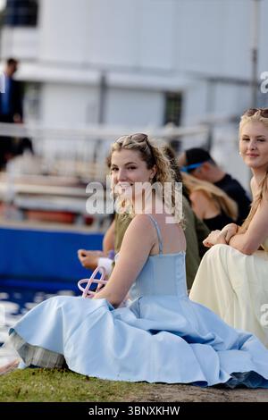 Henley-on-Thames, UK, 4th July 2025. Spectators enjoy the vibrant atmosphere of the Henley Royal Regatta, one of Britain’s most prestigious summer sporting and social events. Visitors dressed in traditional boating blazers, summer dresses, and fascinators line the River Thames to watch the races, cheer on their teams, and celebrate with picnics and champagne. The regatta is known not only for world-class rowing but also for its fashion, people-watching, and quintessentially British charm. Stock Photo