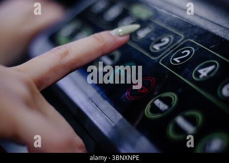 Close up of a finger about to press the number two on a digital control panel device in an elevator or industrial machinery. Showing a person interact Stock Photo