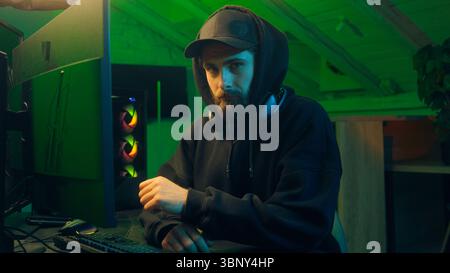Caucasian man hacker computer looking at camera programming pc scam networking male guy spying thief virtual dangerous criminal coding web Stock Photo