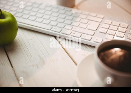 Keyboard with coffee and green apple on table Stock Photo
