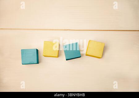 Flat design is showing four wooden blocks in row on wood surface, highlighting teal and yellow Stock Photo