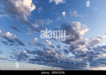 Beautiful white puffy clouds against blue sky during dramatic sunset Stock Photo