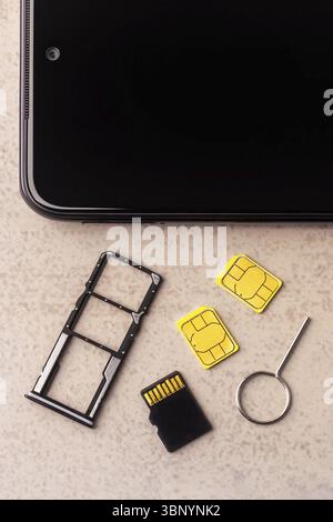 Smartphone and open slots for nano SIM cards, two nano SIM cards, micro SD drive and metal key on grey background Stock Photo