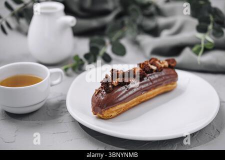 food still-life, Eclair with Chocolate Cream and Hazelnuts and tea Stock Photo