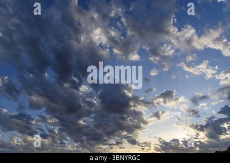 Beautiful white puffy clouds against blue sky during dramatic sunset Stock Photo
