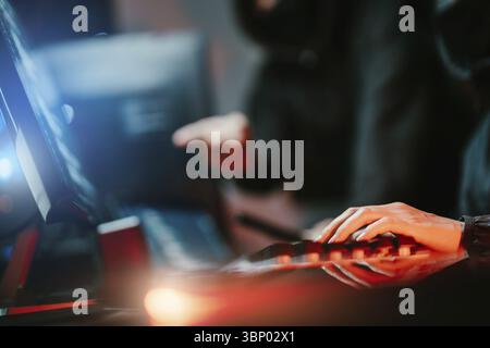 Hacker in dark room using keyboard stealing data on internet Stock Photo