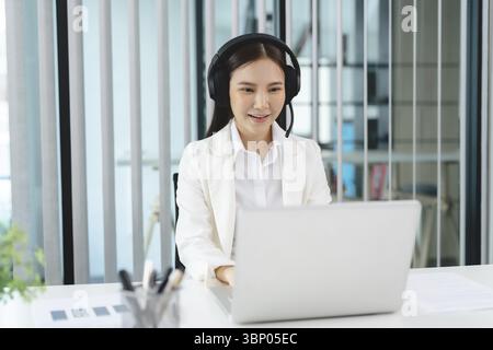 Smiling customer support service operator help desk. Young operator asian woman agent with headsets working support hotline in a call centre Stock Photo
