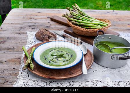 Fresh Asparagus creamy soup on wooden table outside in the garden Stock Photo