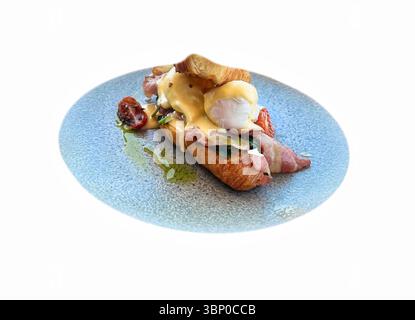 Delicious Eggs Benedict with Hollandaise Sauce and Fresh Parsley Garnish on Plate on a white background Stock Photo