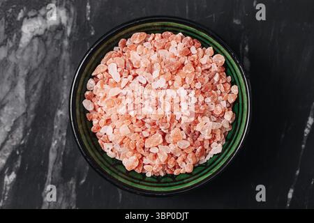 Pink Himalayan salt in a bowl. Natural mineral with coarse crystal texture. Organic seasoning ingredient for cooking and wellness. Stock Photo