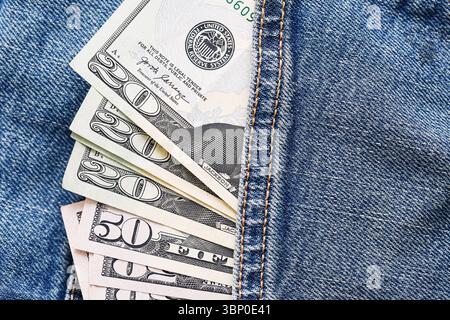 US dollar banknotes in blue jeans pocket. Fifty and hundred dollar bills partially visible. Close-up of money and clothing. Financial symbol of wealth Stock Photo