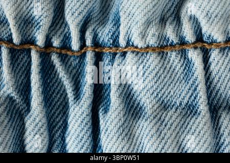 Detailed View of Blue Jeans Fabric and Yellow Thread Stitching. Stock Photo