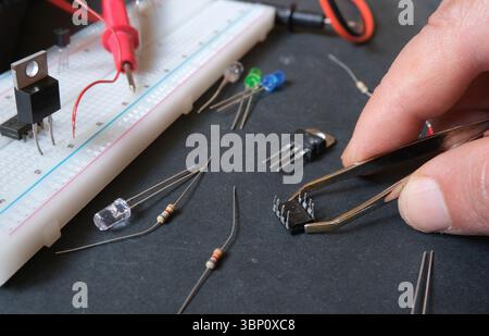 Electronics construction in laboratory. Hands connecting wires to breadboard. The engineer, installing the prototype robot's electronic module. Stock Photo