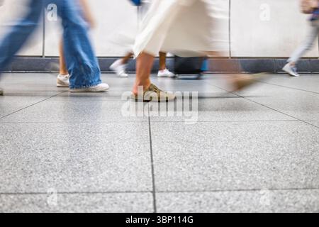Motion blur of anonymous commuters walking indoors on polished urban floor during rush hour Stock Photo