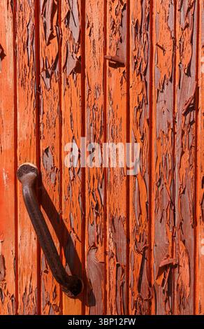 Rusty metal door handle and orange paint peeling off from wooden boards Stock Photo