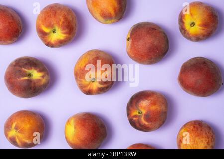 Fruity summer background whole peaches on purple background top view Stock Photo