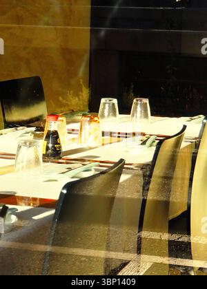 Soy sauce bottle on sunlit table in Japanese restaurant, Milan dining interior with reflections Stock Photo