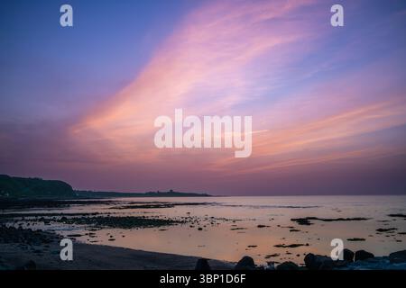 A vibrant sunset with striking cloud formations paints the sky over the rocky coastline of Shimen District New Taipei City Taiwan during twilight. Stock Photo