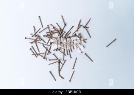 A pile of old, rusty nails spread randomly over a white background. Stock Photo