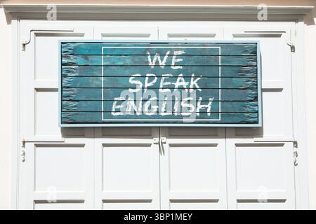 We Speak English text on advertising board outdoors. Language course Stock Photo