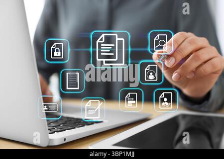 Woman working on laptop at table, closeup, Different document icons on virtual screen Stock Photo