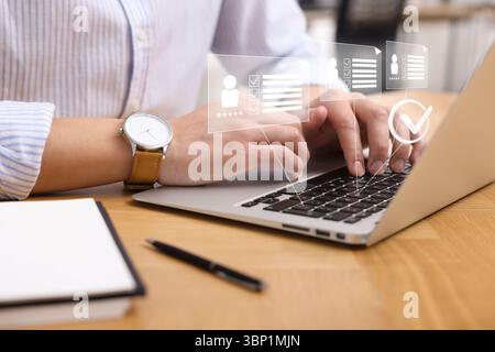 Human resources manager working on laptop at table, closeup. Virtual check mark and resumes over computer Stock Photo