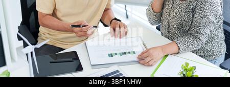 Asian business professionals analyze sustainable development charts in an office meeting focused on environmental social governance data Stock Photo