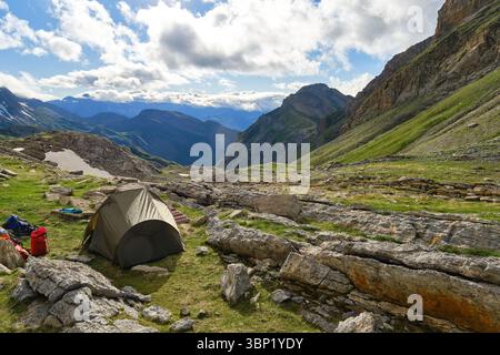 Green tent set up at the base of a rocky mountain, enjoying the base ...