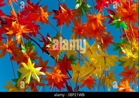 Pattern of colorful plastic maple leaves decoration against a clear blue sky brightens up a shopping district in Asakusa, Tokyo, Japan. Stock Photo