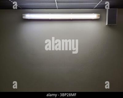 Cold LED light on the wall in the dark with free space for text below. Stock Photo