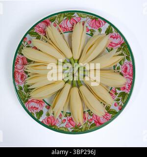 Fresh white champak flowers arranged in circle on vintage ceramic plate with pink floral pattern, top view still life, calm and elegant mood. Stock Photo