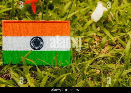 India national flag IN flag eco friendly embroidered on grass with red and white flower petals. Concept for earth day, environment and climate change. Stock Photo