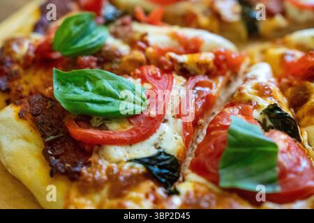 Pizza basil tomatoes: Freshly baked pizza, topped with basil, and tomatoes, served immediately for a flavorful meal. Stock Photo