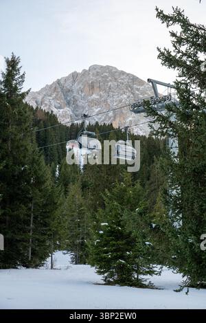 A ski lift is seen in the background of a snowy forest. The lift is surrounded by trees and snow, creating a serene and peaceful atmosphere. Concept o Stock Photo