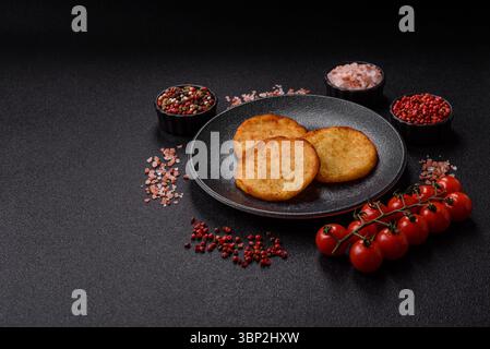 Hash browns, a breakfast food made of potatoes, onions and vegetables. Hash browns with potatoes, salt and spices on a dark concrete background Stock Photo