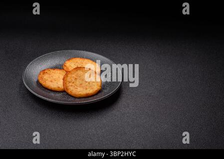 Hash browns, a breakfast food made of potatoes, onions and vegetables. Hash browns with potatoes, salt and spices on a dark concrete background Stock Photo