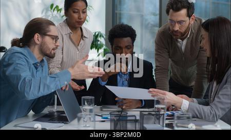 Business team multiracial group talking discussion graph chart document report analyzing men women in office coworkers African American Indian Stock Photo