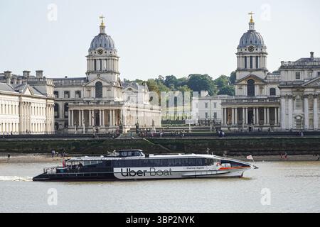 Thames clipper, Uber Boat passing the University of Greenwich, the Old Royal Naval College in London England United Kingdom UK Stock Photo
