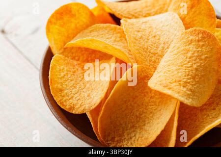 Crispy Potato Chips in Clay Bowl on Rustic Table Stock Photo
