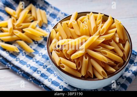 Penne Pasta in Bowl on Blue White Kitchen Towel Wooden Background Stock Photo