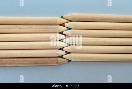 Close-up of Two groups brown crayons are placed sharp tips facing collide to each other stand in a neat row. Wooden pencils arranged in a symmetrical Stock Photo